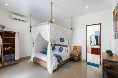 a bedroom with a bed with a mosquito net at MasBro ART Villas in Seminyak