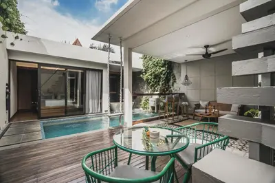 a patio with a glass table and chairs next to a swimming pool at Ayona Villa Seminyak by Ini Vie Hospitality in Seminyak