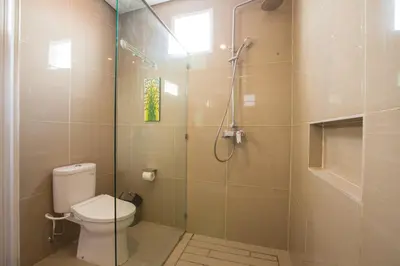 a bathroom with a toilet and a glass shower at Villa Ultima Umalas in Canggu