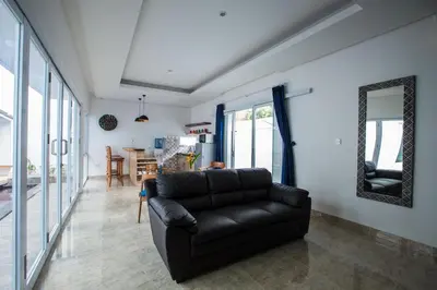 a black leather couch in a living room with a mirror at Villa Ultima Umalas in Canggu