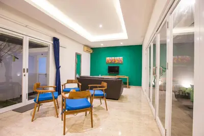 a living room with green walls and blue chairs at Villa Ultima Umalas in Canggu