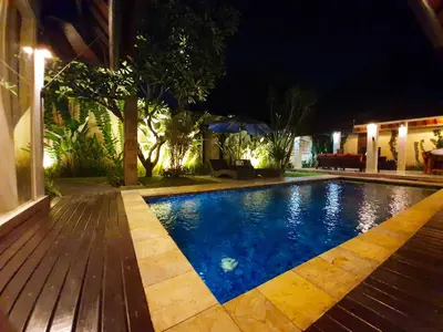 a swimming pool in a backyard at night at Villa Davenny in Seminyak