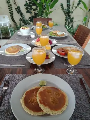 a table with plates of food and glasses of orange juice at Villa Davenny in Seminyak