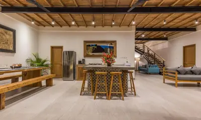 a large living room with a kitchen and a staircase at Villa Jamu in Seminyak