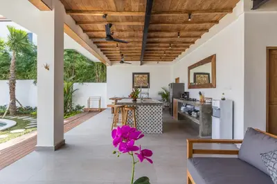 an open kitchen and living room with wooden ceilings at Villa Jamu in Seminyak