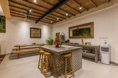 an open kitchen with a large island with bar stools at Villa Jamu in Seminyak