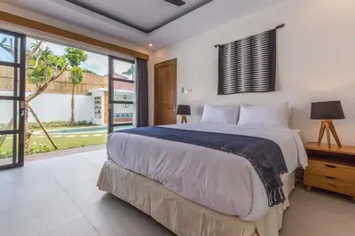 a bedroom with a large bed and a large window at Villa Jamu in Seminyak