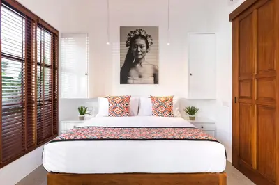 a bedroom with a large bed with a black and white picture at Villa Karang in Seminyak