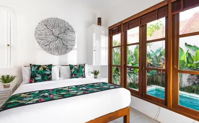 a bedroom with a bed and a large window at Villa Pandi in Seminyak