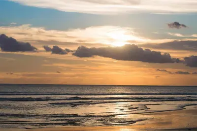 a sunset on a beach with the ocean at Capital O 2166 Elitya Stay in Sanur