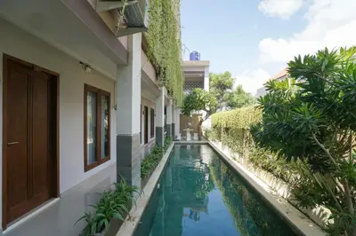 a house with a swimming pool next to a building at Capital O 2166 Elitya Stay in Sanur
