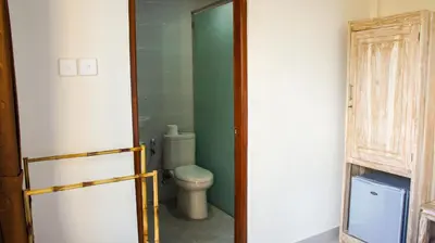 a bathroom with a toilet and a green wall at Dana Homestay in Canggu