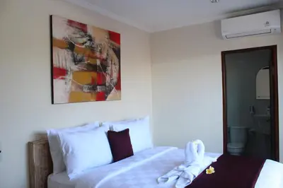 a bedroom with a bed and a painting on the wall at Dana Homestay in Canggu