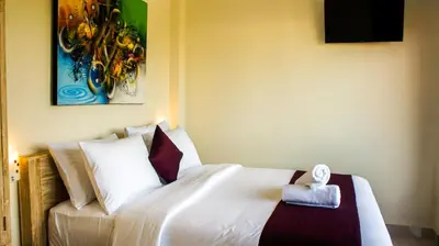a bedroom with a white bed and a painting on the wall at Dana Homestay in Canggu