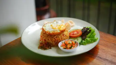 a plate of food with rice and vegetables on a table at Del Cielo Villa Seminyak in Seminyak