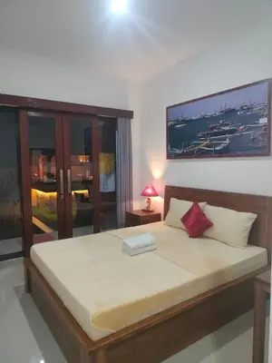 a bedroom with a large bed with a picture on the wall at D&D homestay in Pesanggaran