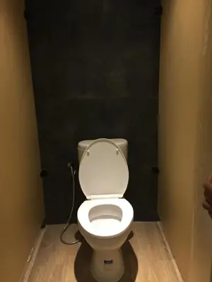 a white toilet in a bathroom with a black wall at XOXO Kuta Legian Hostel in Legian