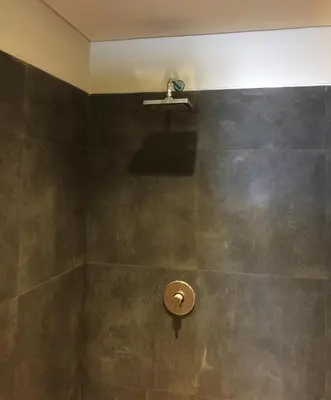 a bathroom with a shower with a wall at XOXO Kuta Legian Hostel in Legian