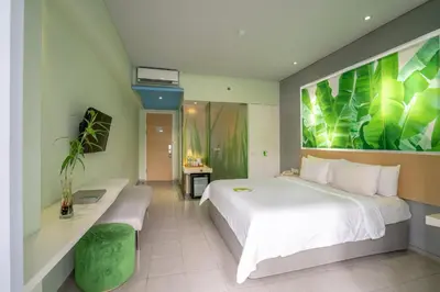 a bedroom with a large white bed with a green painting on the wall at EDEN Hotel Kuta Bali in Kuta