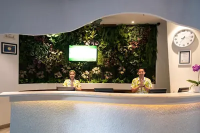 two people sitting at a table in front of a green wall at EDEN Hotel Kuta Bali in Kuta
