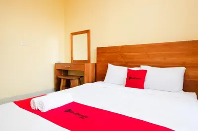 a bedroom with a white bed with red pillows at RedDoorz @ Kerta Dalem Sidakarya in Denpasar