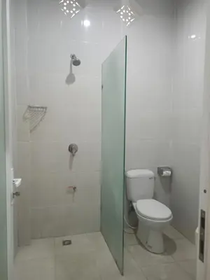 a bathroom with a toilet and a glass shower at Adijaya homestay in Seminyak