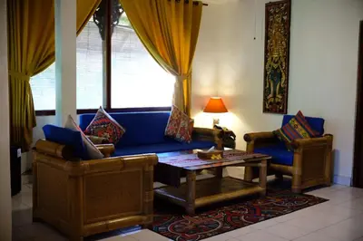 a living room with a blue couch and two chairs at Puri Cendana Resort Bali in Seminyak