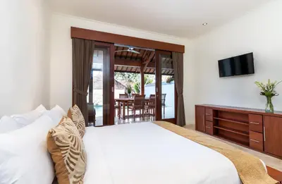 a bedroom with a white bed and a television at Villa Lalang Temu in Jimbaran