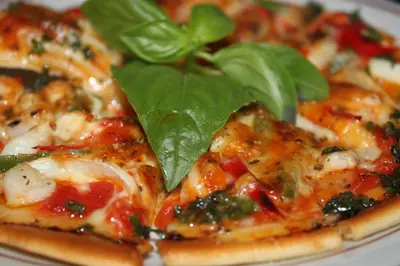 a pizza with a green leaf on top of it at Bakung Beach Resort in Kuta