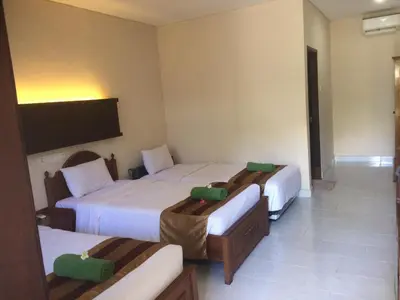 a hotel room with three beds and a flat screen tv at Bakung Beach Resort in Kuta