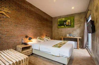 a bedroom with a bed and a brick wall at Bali Breezz Hotel in Jimbaran