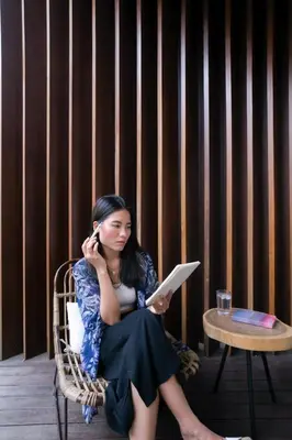 a woman sitting in a chair talking on a cell phone at Pelangi 148 Beach Suites in Seminyak