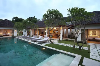 a swimming pool with lounge chairs and a house at Villa Bali Asri Batubelig in Seminyak