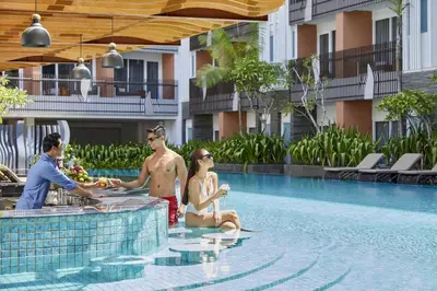 a group of people sitting next to a swimming pool at Fairfield by Marriott Bali Kuta Sunset Road in Kuta