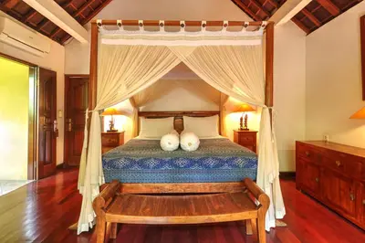a bedroom with a canopy bed and a wooden floor at Villa Plawa Asri in Seminyak