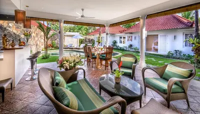 an outdoor patio with chairs and tables and a dining area at Hevea Villas in Seminyak