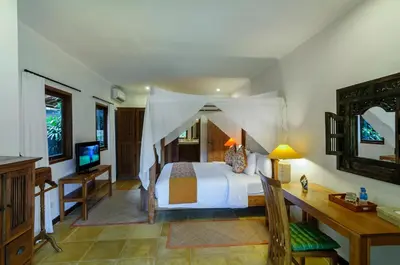 a bedroom with a bed and a desk and a television at Hevea Villas in Seminyak