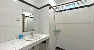 a white bathroom with a sink and a mirror at Sanur Lodge in Sanur