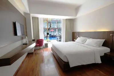 a bedroom with a white bed and a red chair at The Bene Hotel in Kuta