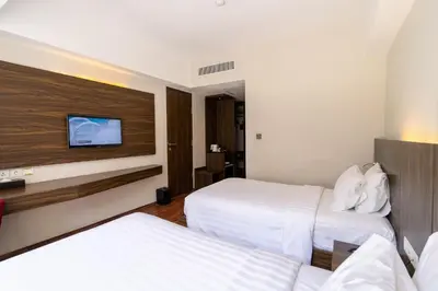 a hotel room with two beds and a flat screen tv at The Bene Hotel in Kuta