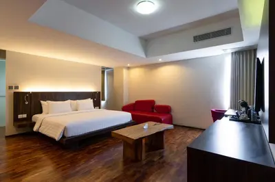 a hotel room with a bed and a red chair at The Bene Hotel in Kuta
