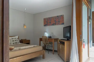 a bedroom with a bed and a desk with a television at Balinea Holiday Home in Kerobokan