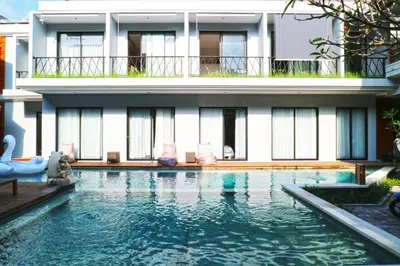 a house with a swimming pool in front of a building at Gemini Star Hotel Kuta in Kuta