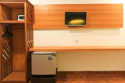 a room with a desk with a television on a wall at Ayu Lili Garden Hotel Kuta in Kuta