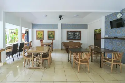 a dining room with tables and chairs and a tv at Ayu Lili Garden Hotel Kuta in Kuta