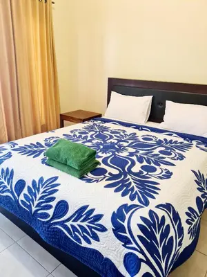 a blue and white bed with a green pillow on it at Guest house KupuKupu39 in Kuta