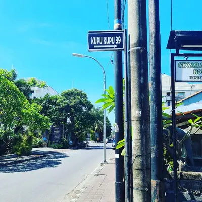 a street sign on a pole on a city street at Guest house KupuKupu39 in Kuta