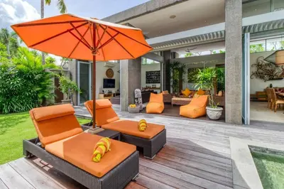 an outdoor patio with orange chairs and an umbrella at Aramanis in Seminyak