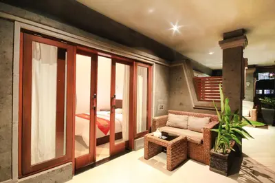 a room with a balcony with a bed and a chair at Letos Kubu Homestay in Kuta