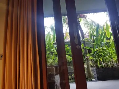 a window with a view of a palm tree at Letos Kubu Homestay in Kuta